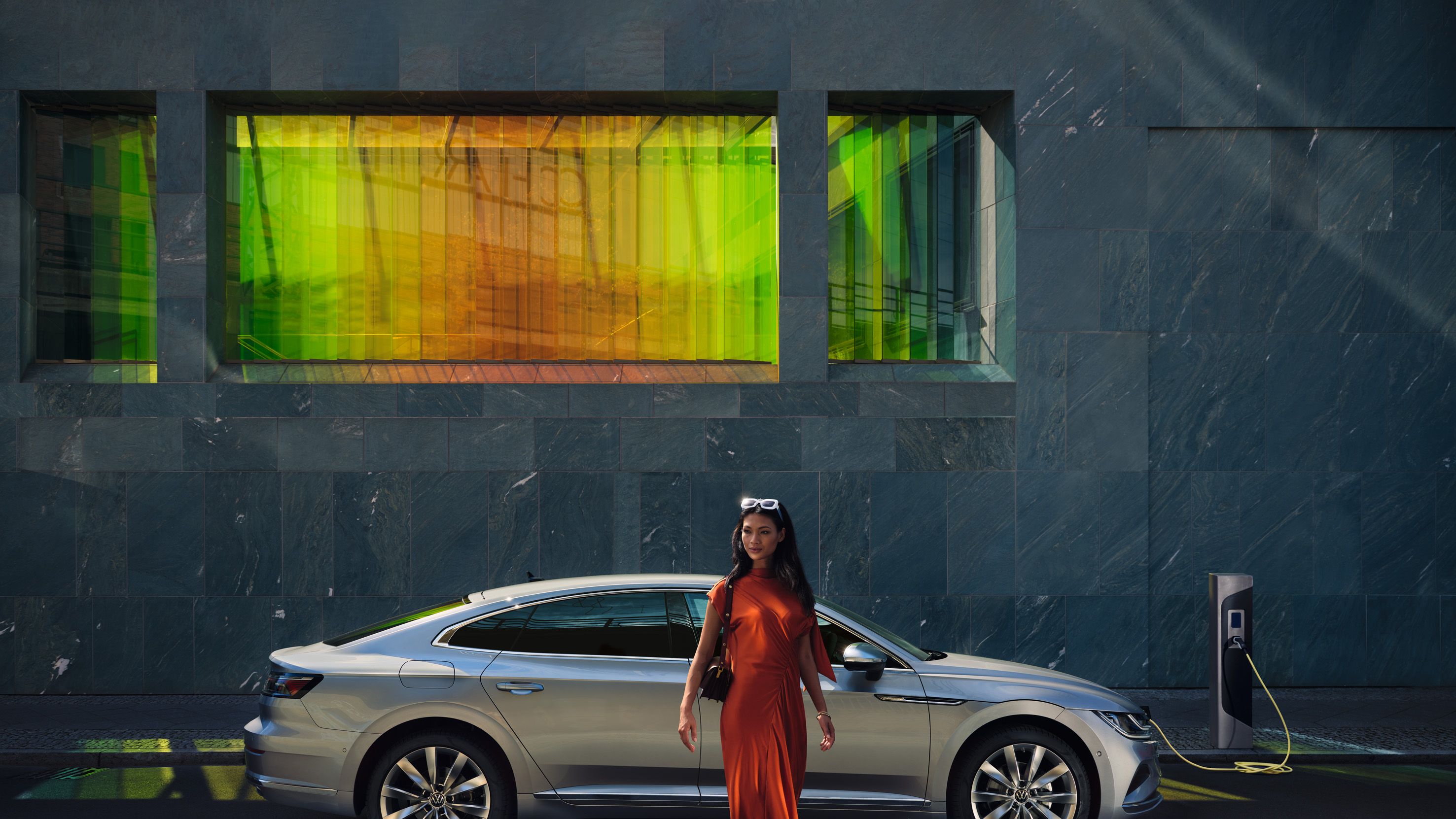 VW Arteon steht seitlich an einer Ladesäule und ist mit Ladekabel verbunden