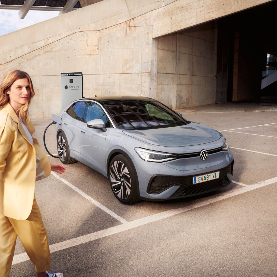 Ženska hodi do sivega VW ID.5, ki se polni na polnilni postaji MOON. 