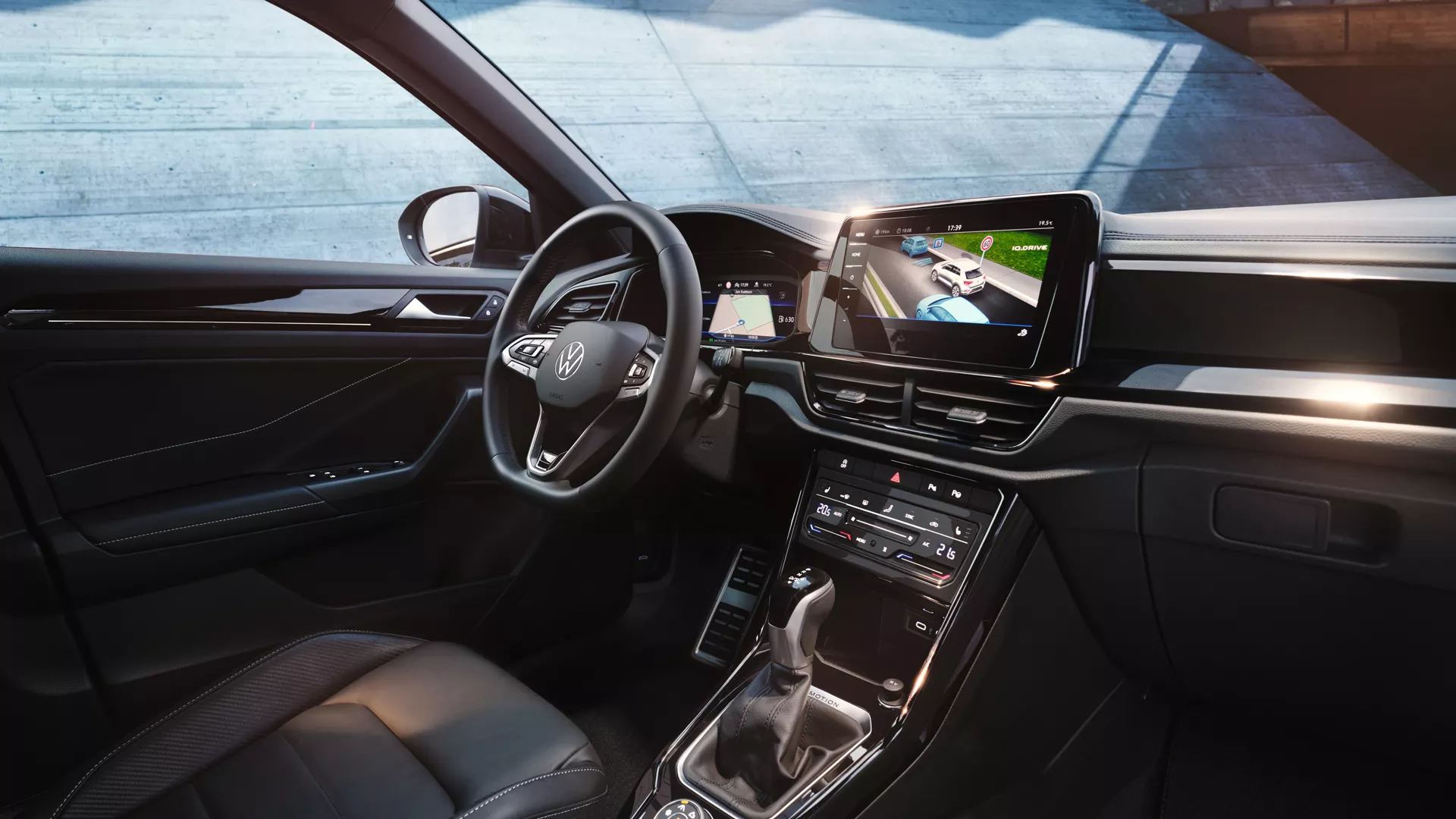 Notranjost VW T-Roca, pogled s sovoznikovega na voznikov sedež in armaturno ploščo z večfunkcijskim volanom in infotainment sistemom.