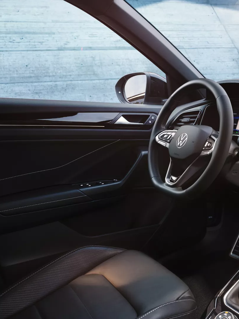 Notranjost VW T-Roca, pogled s sovoznikovega na voznikov sedež in armaturno ploščo z večfunkcijskim volanom in infotainment sistemom.