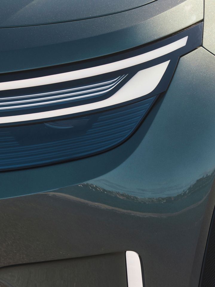 Bližnji posnetek avtomobilskega žarometa in dela blatnika sodobnega vozila. Žaromet ima elegantno, ukrivljeno LED zasnovo. 