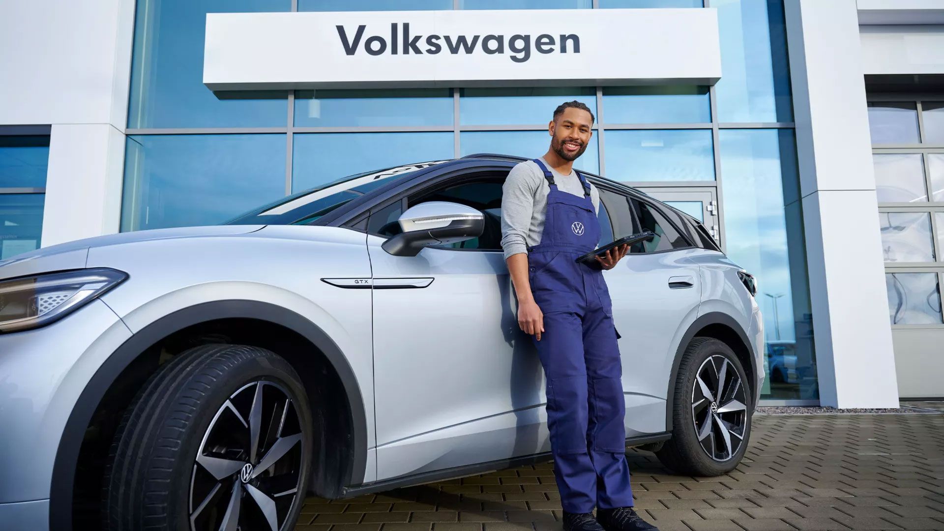 Ein VW Servicetechniker mit Tablet steht vor einem VW ID.