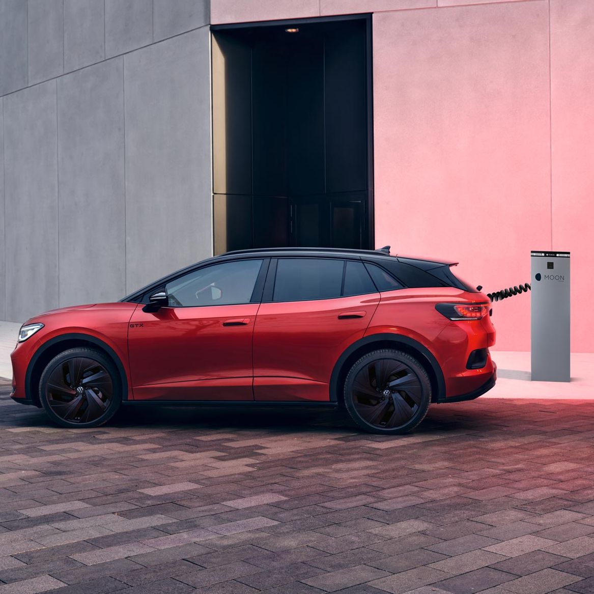 Seitenansicht eines roten VW ID.4 GTX der an Ladesäule geladen wird