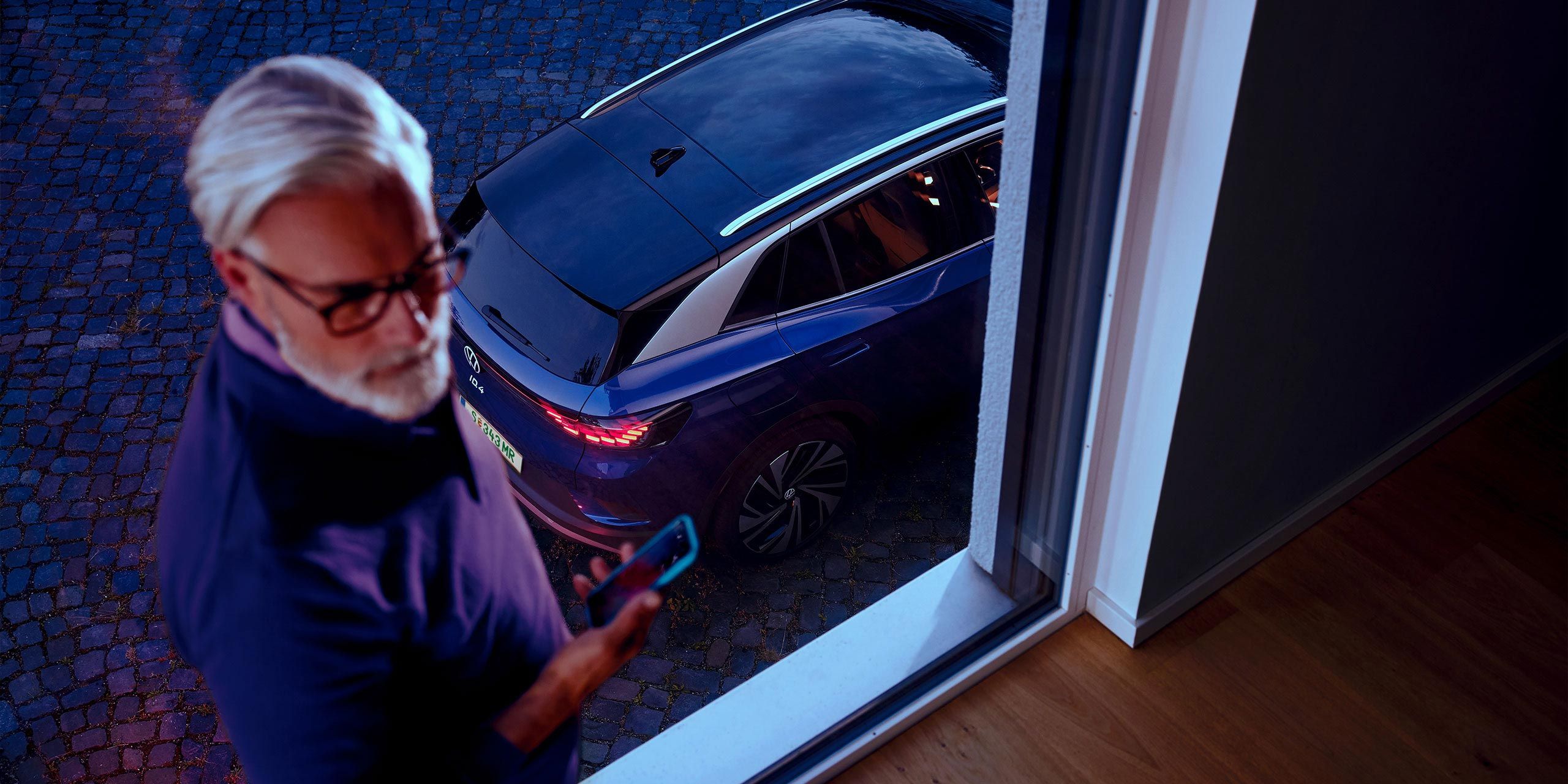 Ein Mann neben einem VW ID.4 in Blau. 