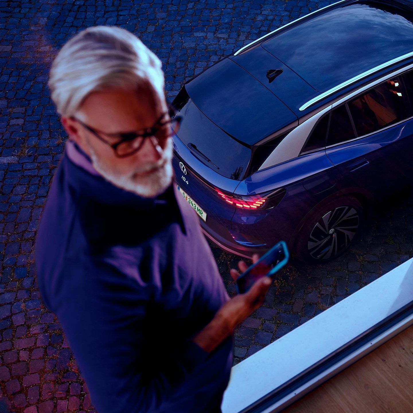 Ein Mann neben einem VW ID.4 in Blau. 