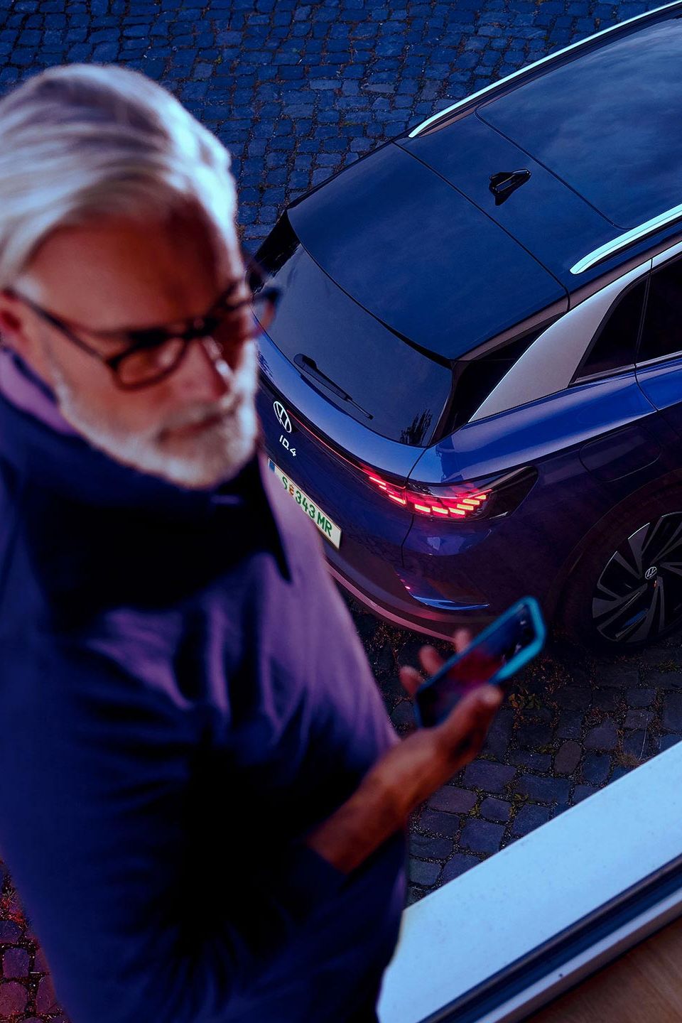 Ein Mann neben einem VW ID.4 in Blau. 