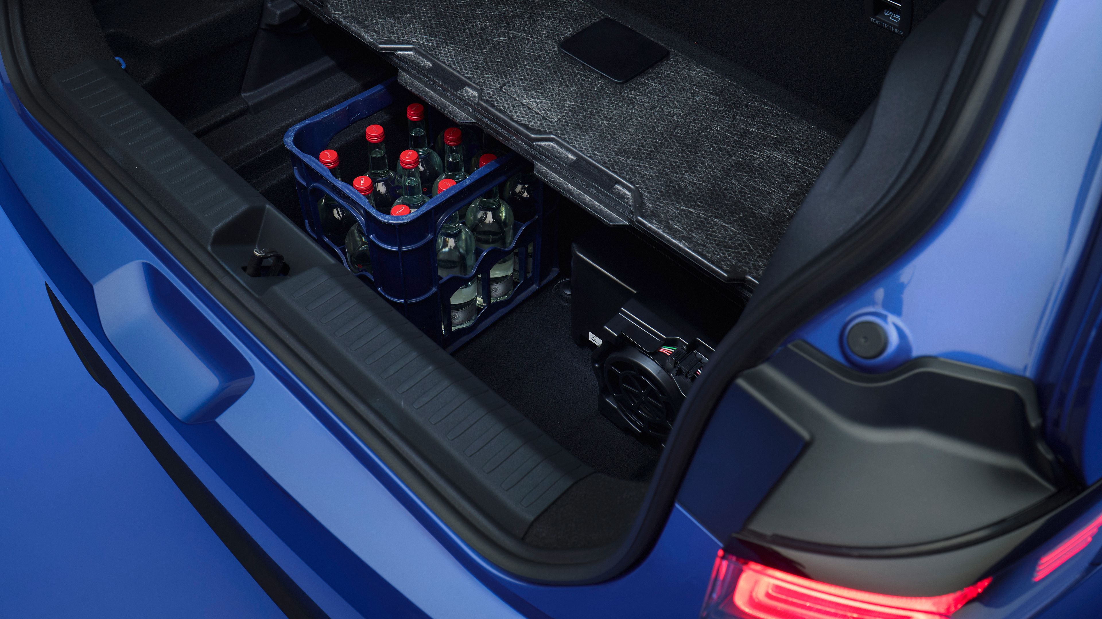 Prtljažni prostor ID. Pola z dvignjenim dnom razkriva skrit spodnji predal. V predalu je moder zaboj s steklenicami pijače, ob njem pa avtomobilska oprema.