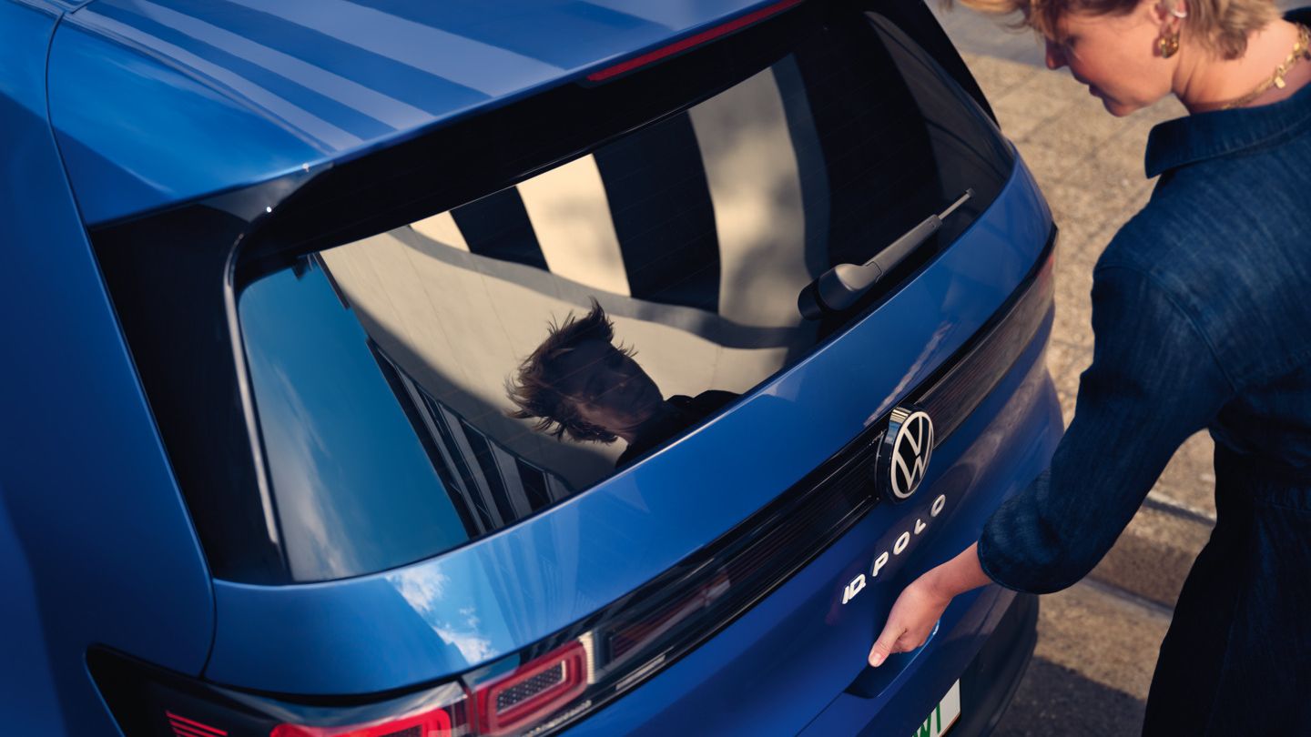 Ženska odpre pokrov prtljažnika modrega VW ID-ja. Polo Style.