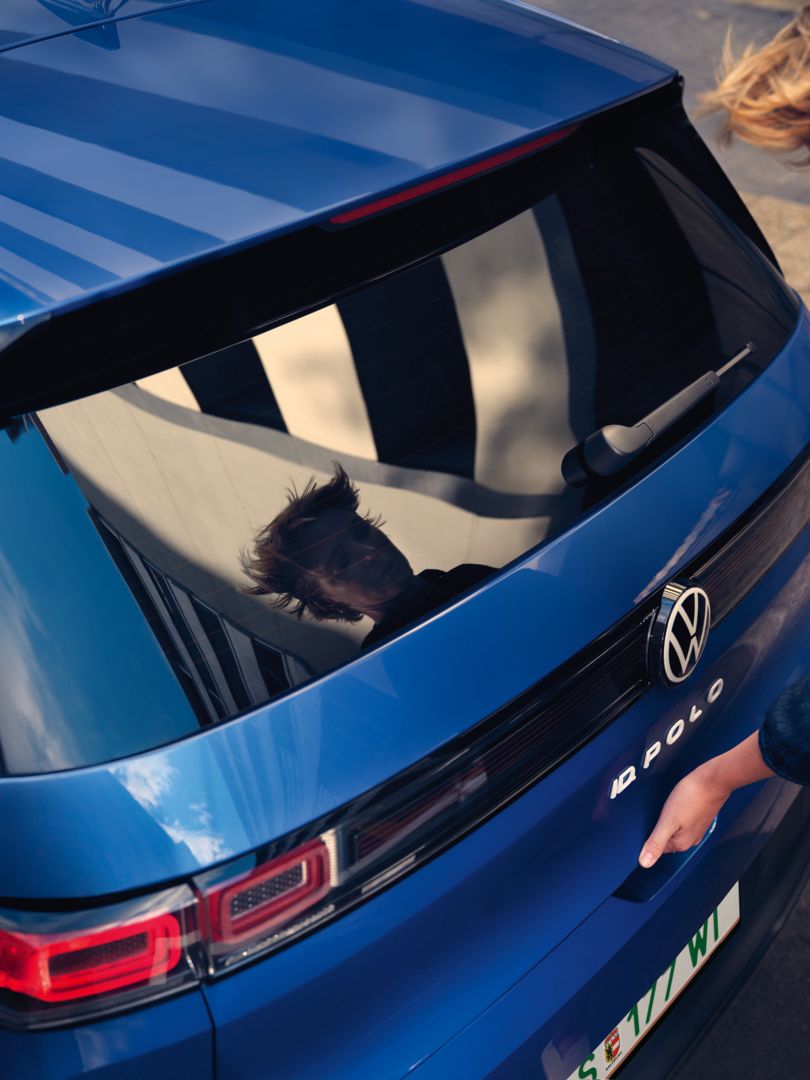 Ženska odpre pokrov prtljažnika modrega VW ID-ja. Polo Style.