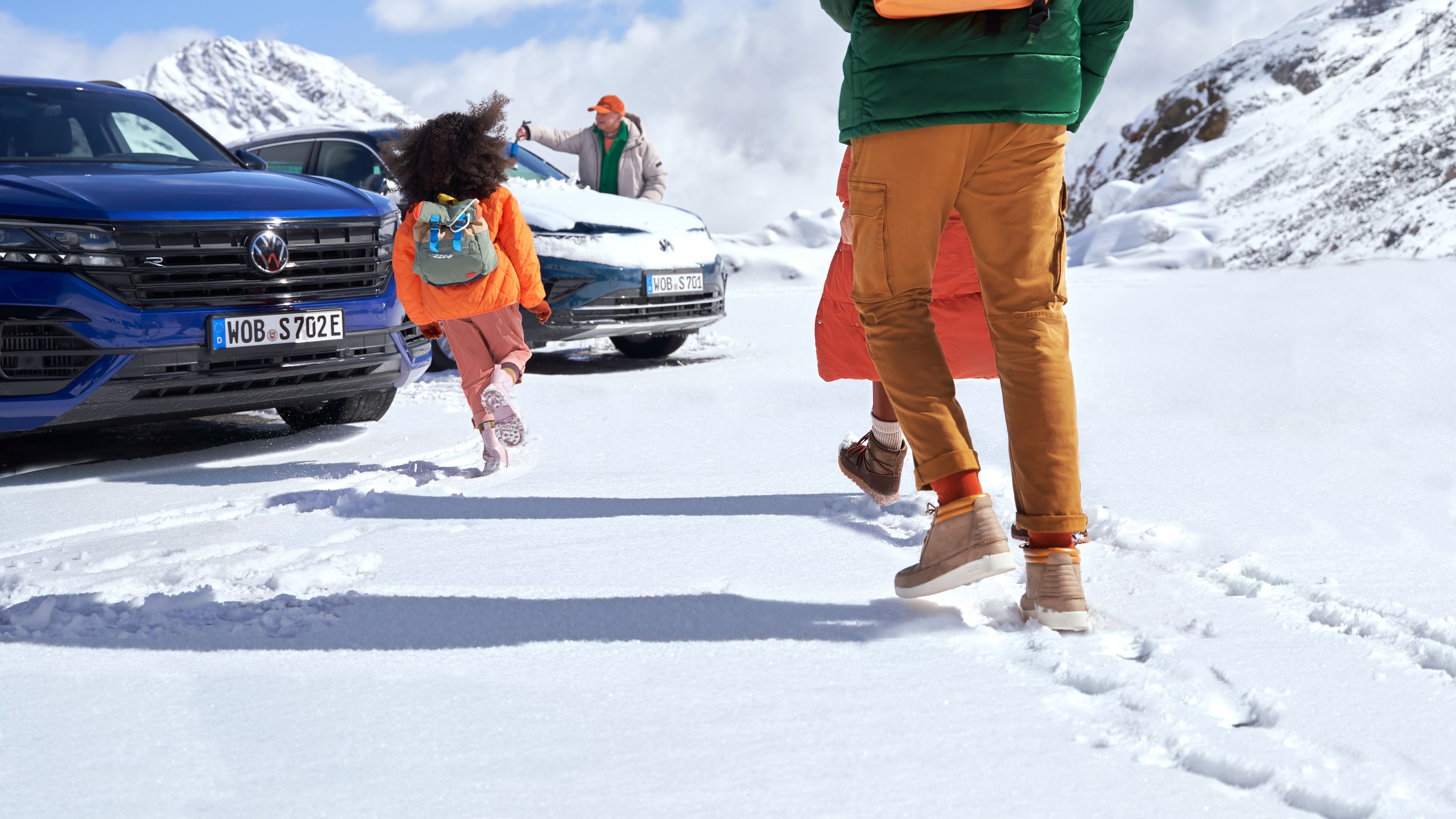 Familie läuft im Schnee auf ihren Volkswagen zu