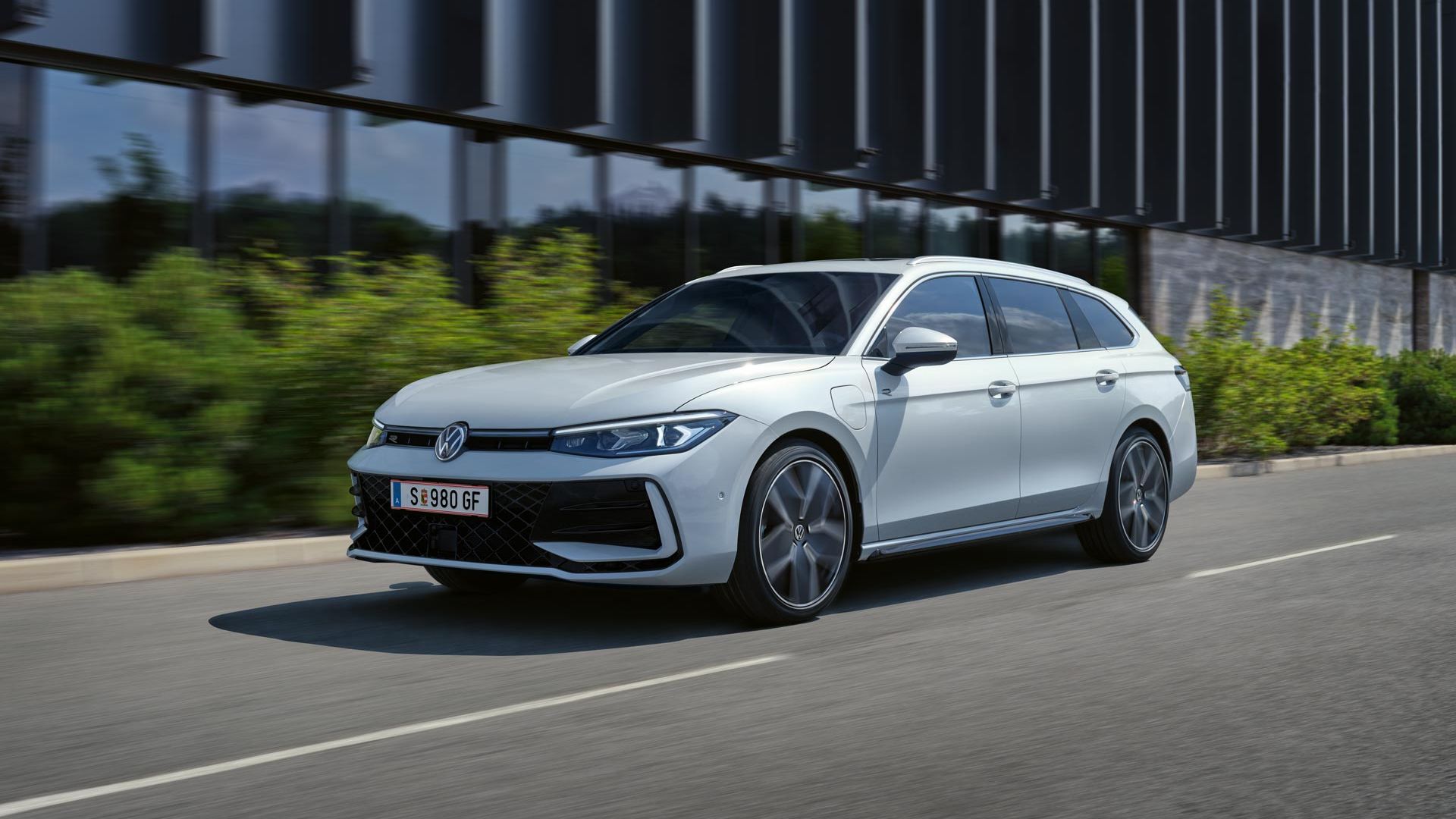 Bel VW Passat je parkiran bočno pred stavbo.