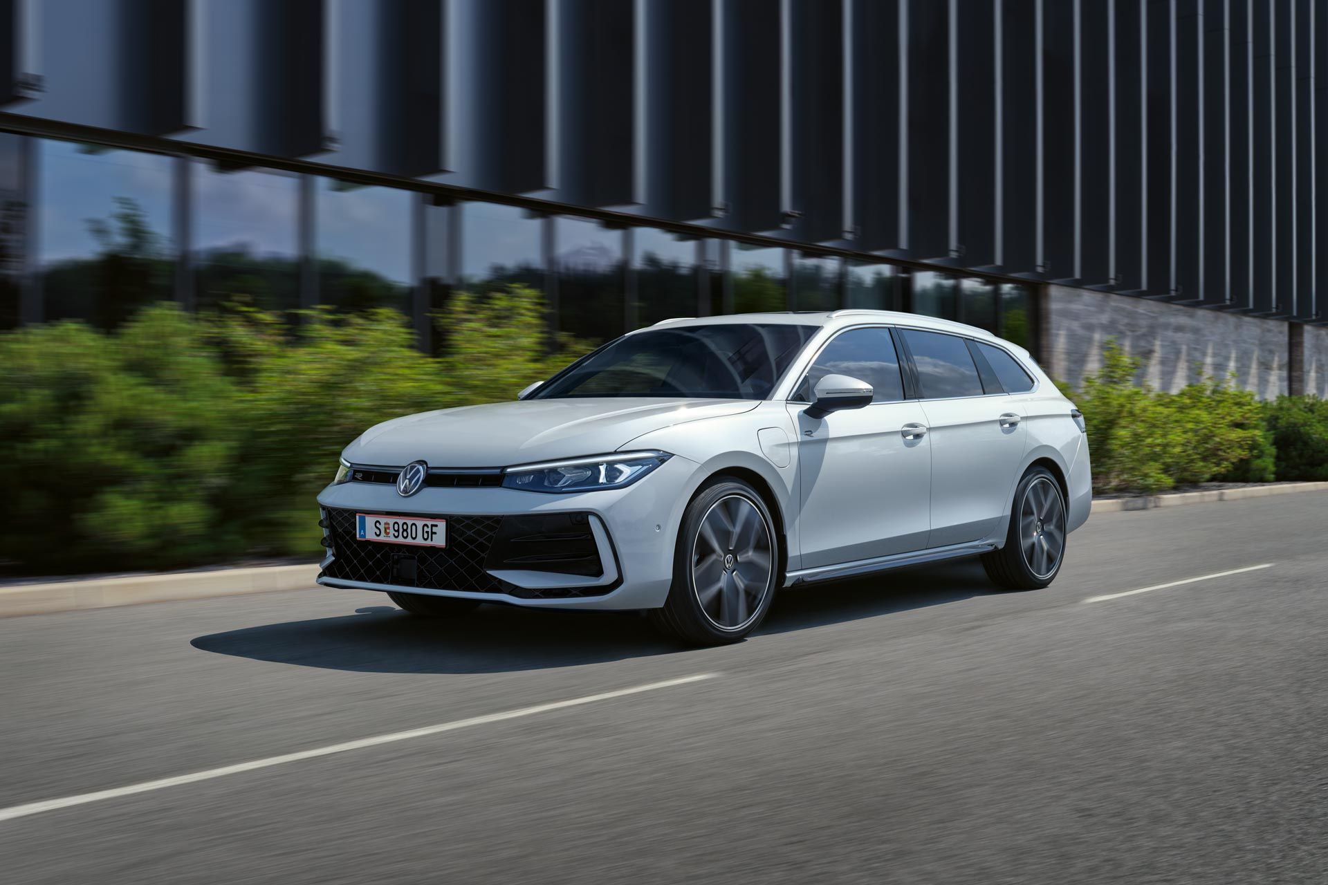 Bel VW Passat je parkiran bočno pred stavbo.