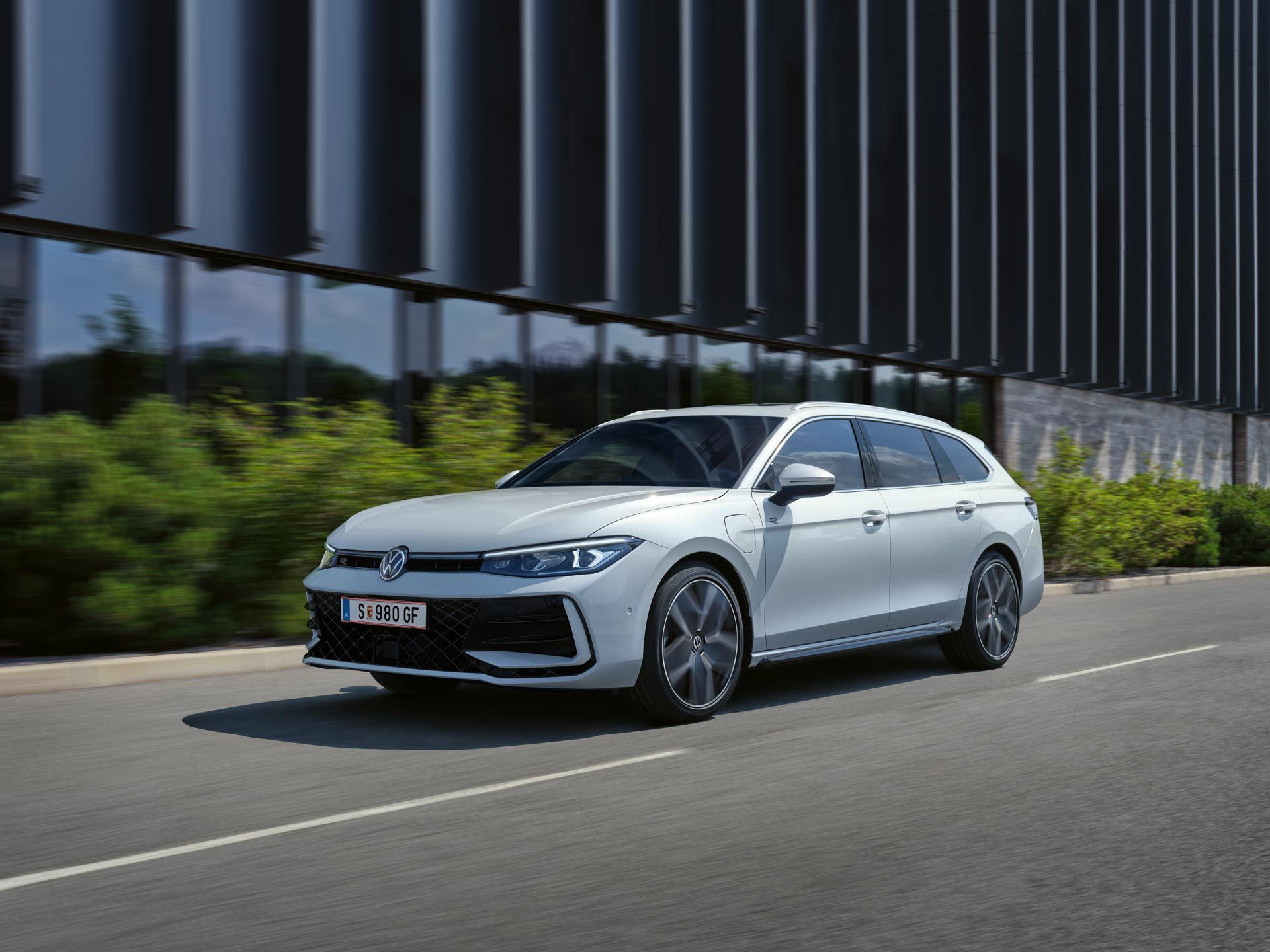 Bel VW Passat je parkiran bočno pred stavbo.