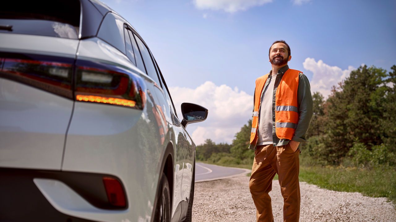  Mann steht vor seinem Volkswagen in einer Warnweste