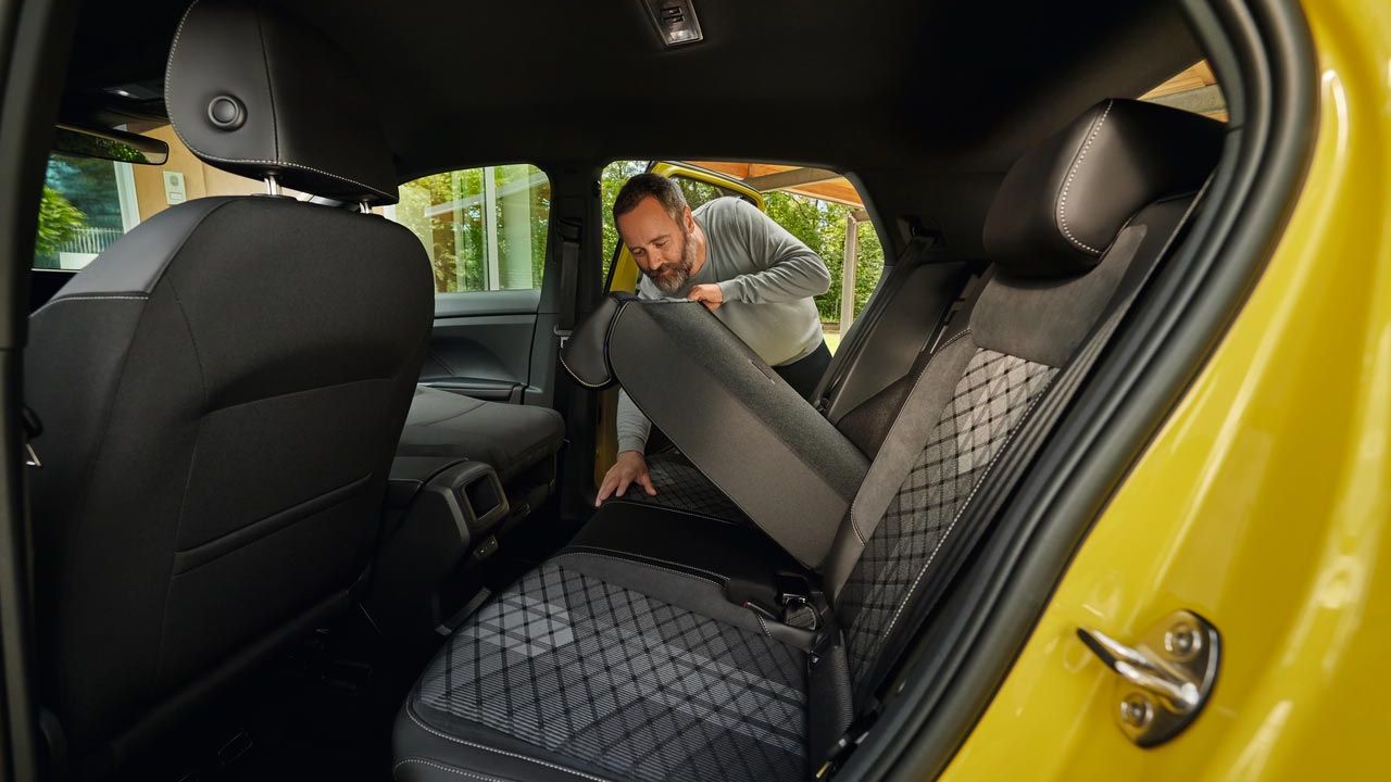Moški podira naslonjalo zadnjega sedeža v rumenem VW T-Crossu.