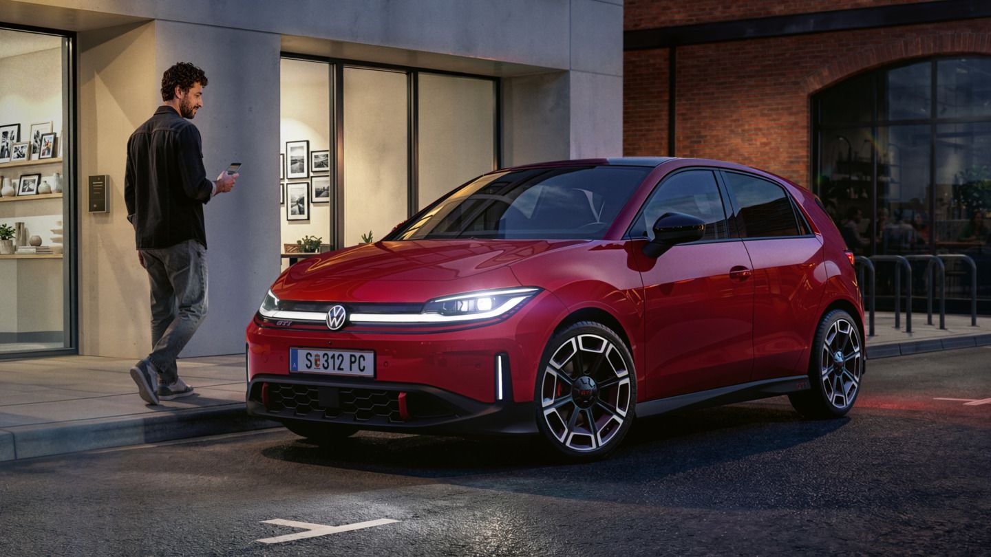 Oseba gre mimo rdečega VW ID-ja. Polo GTI, parkiranega pred sodobno stavbo.