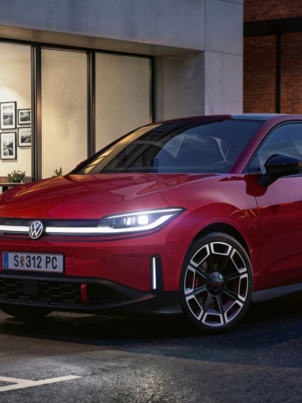 Oseba gre mimo rdečega VW ID-ja. Polo GTI, parkiranega pred sodobno stavbo.