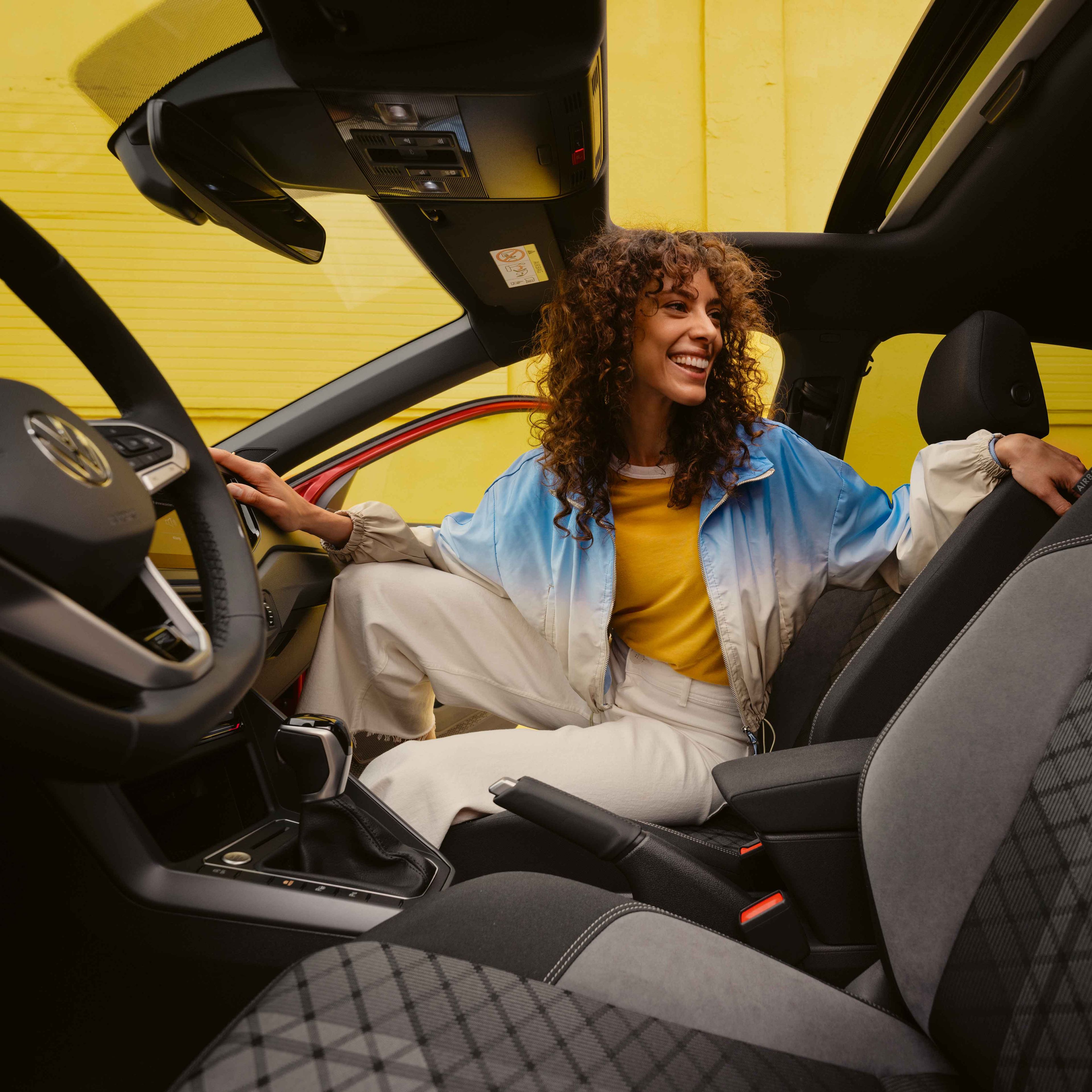 Notranjost izvedbe VW Taigo R-Line: ženska sedi na sovoznikovem sedežu in gleda nazaj