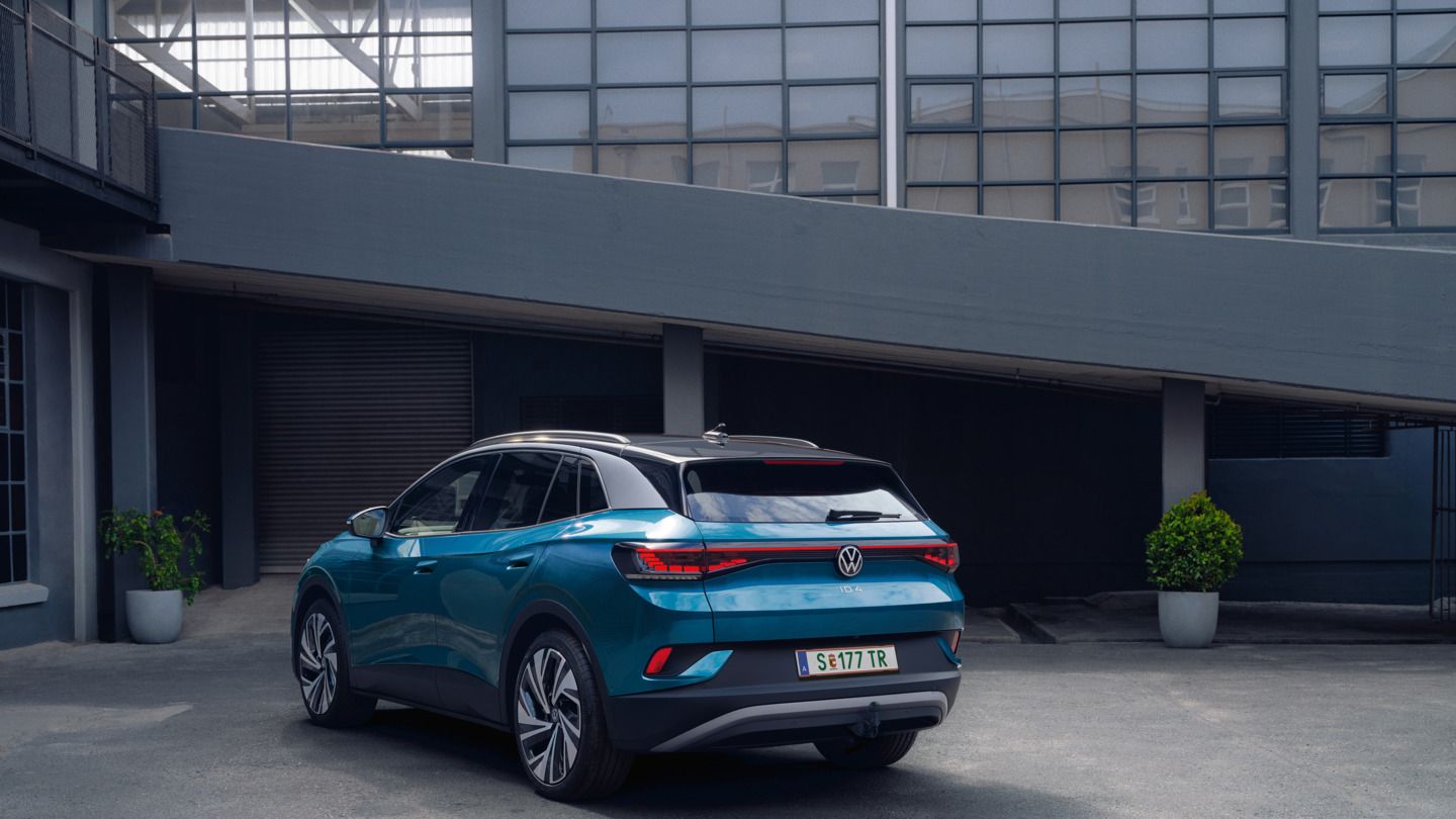 Moder VW ID.4 je od zadaj prikazan na dvorišču industrijske stavbe.