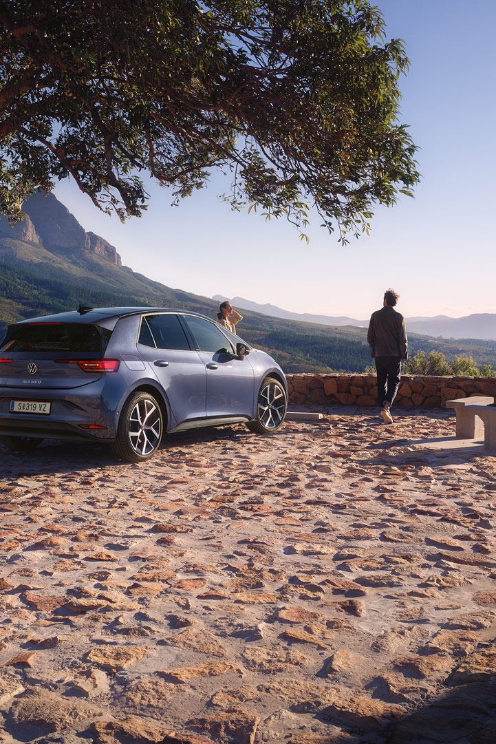 Modri VW ID.3 Neo je parkiran na parkirišču v gorah, ženska in moški uživata v razgledu