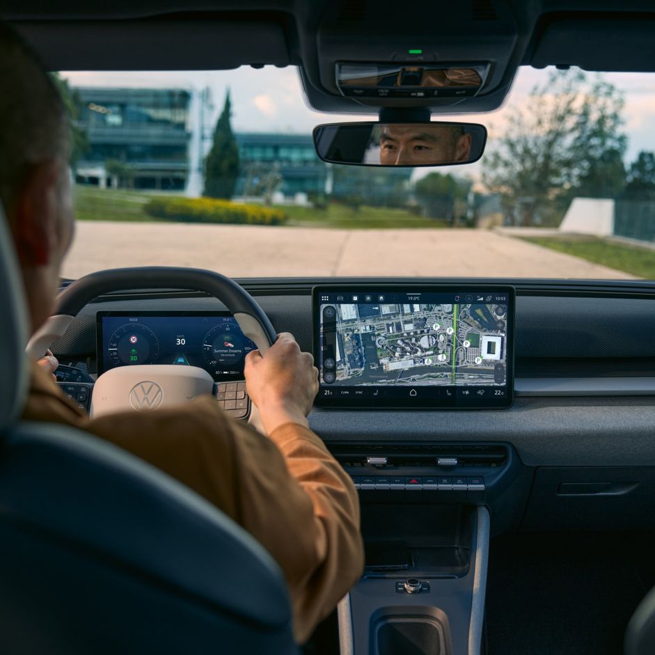 Pogled iz zadnjega sedeža v voznikovo kabino na VW ID. Cross z aktivno navigacijo na zaslonu informacijske zabave.