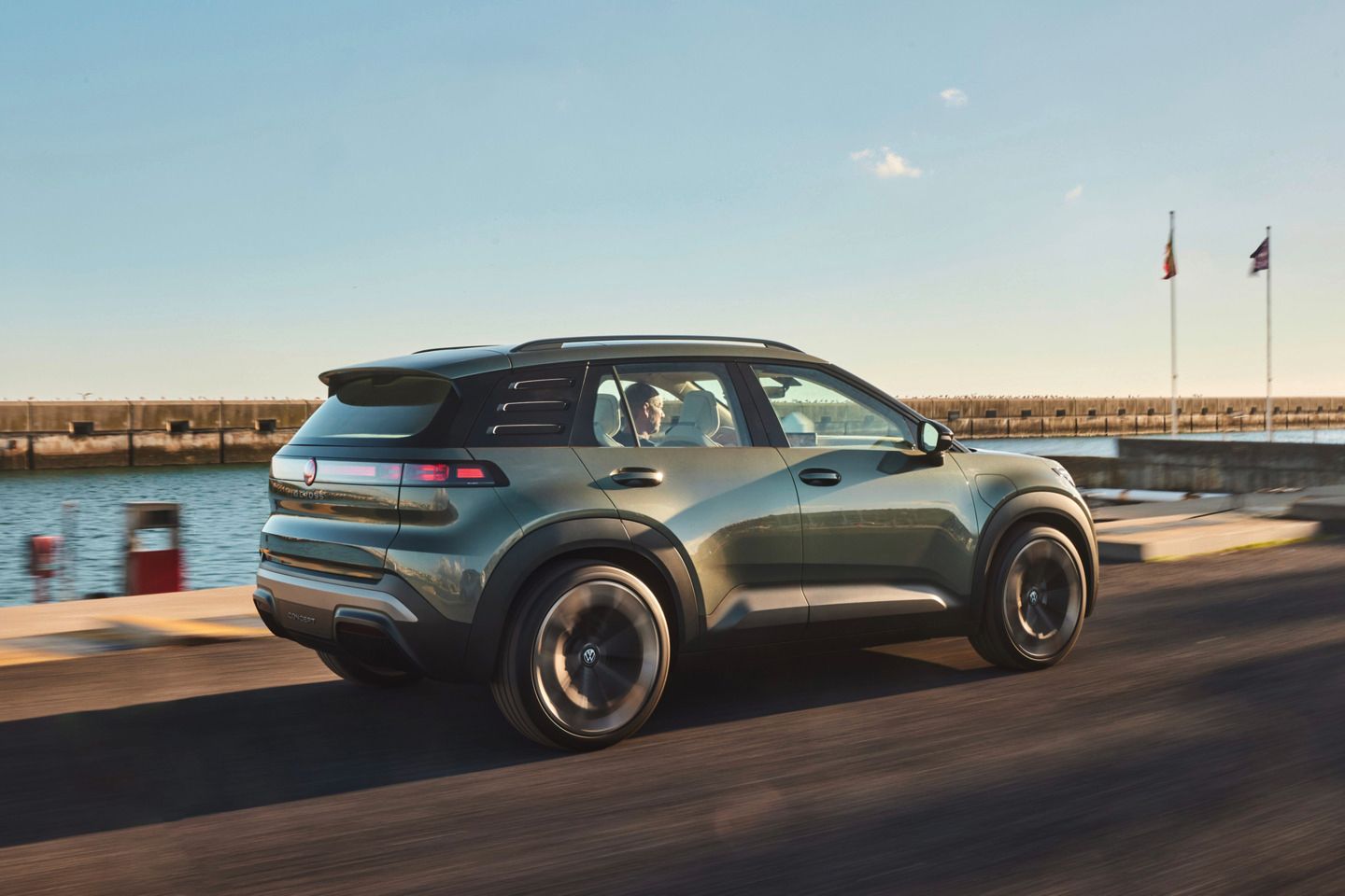 Stranski pogled od zadaj na VW ID. CROSS, ki vozi po obalni cesti.