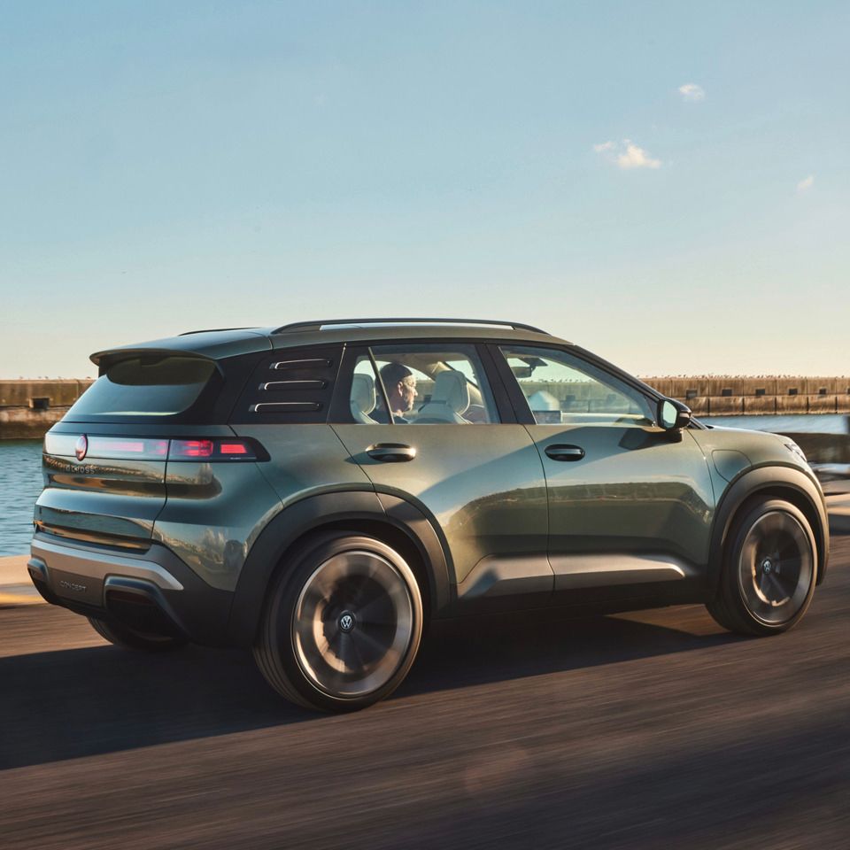 Stranski pogled od zadaj na VW ID. CROSS, ki vozi po obalni cesti.