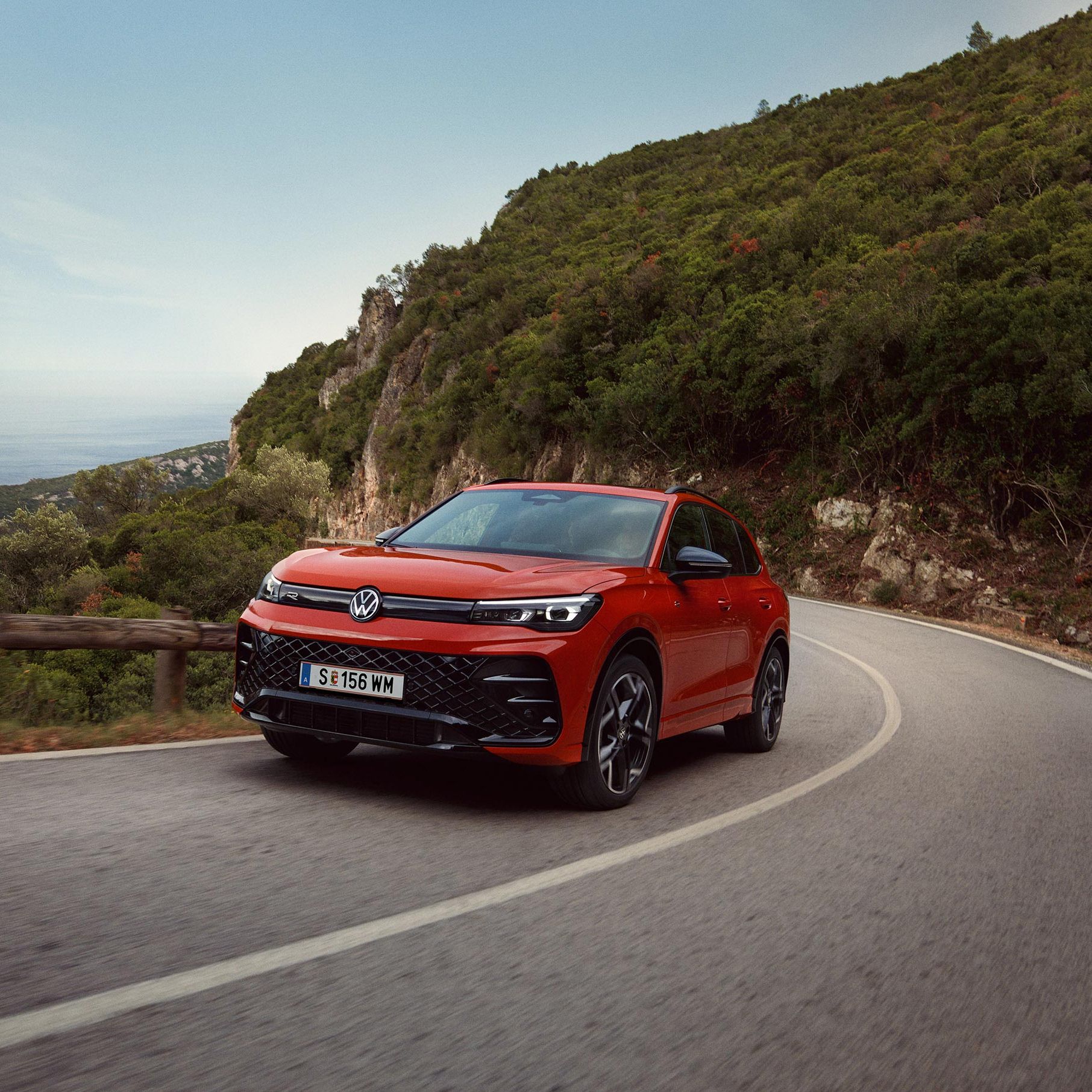 Rdeči VW Tiguan, ki vozi po ovinkasti cesti.