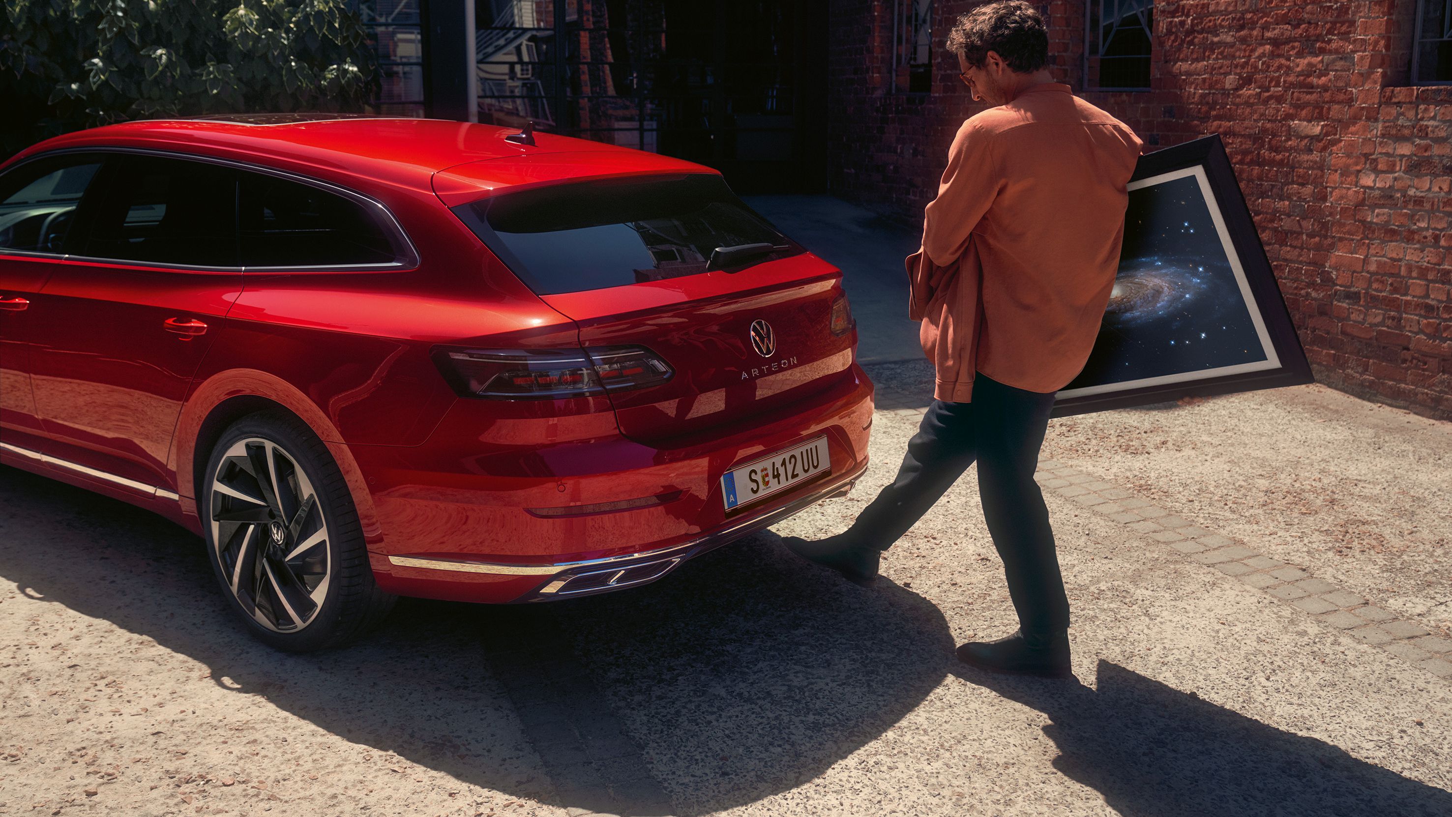Moški pri VW Arteonu Shooting Brake odpira prtljažnik z gibom z nogo, kar omogoča funkcija Easy Open & Close.