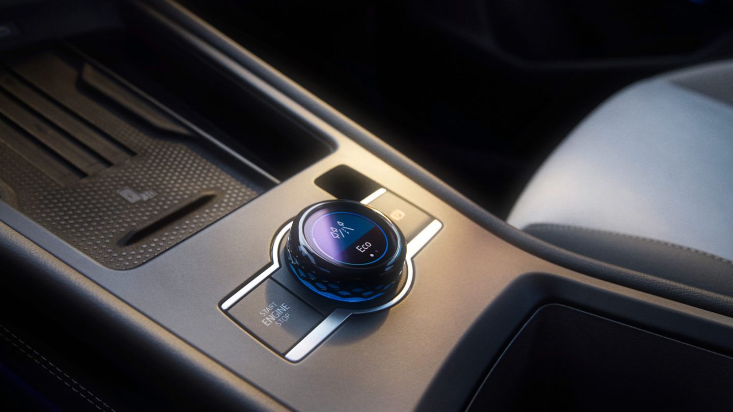 Bližnji posnetek sredinske konzole v T-Rocu s poudarkom na gumbu za doživetje vožnje. Vidni so visokokakovostni materiali in eleganten dizajn.