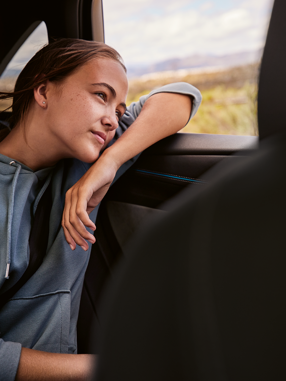 Mlada ženska na zadnjem sedežu VW ID.7 gleda skozi okno.