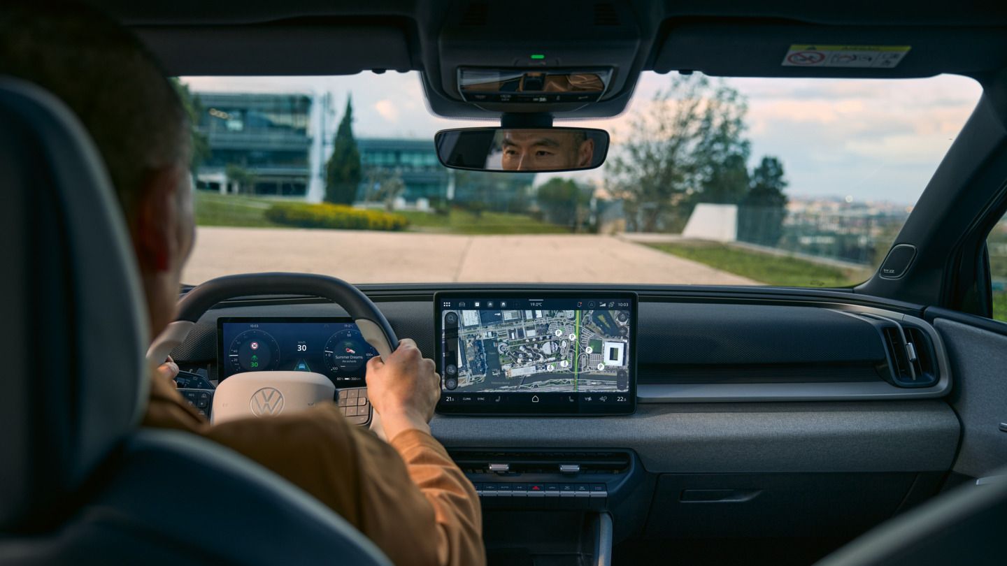 Pogled iz zadnjega sedeža v voznikovo kabino na VW ID. Cross z aktivno navigacijo na zaslonu informacijske zabave.