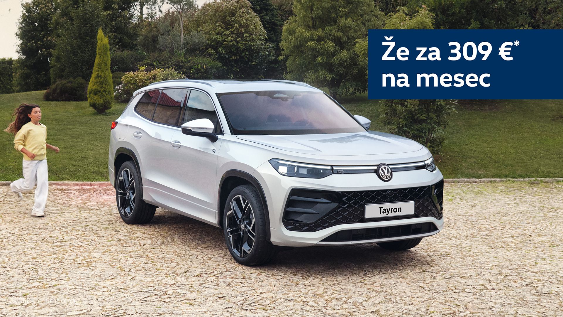 Parkirano belo vozilo VW Tayron na tlakovani površini, z napisom "Že za 309 € na mesec" v zgornjem desnem kotu. V ozadju je zeleno grmičevje. Oseba v belem oblačilu je deloma zamegljena na levi strani.
