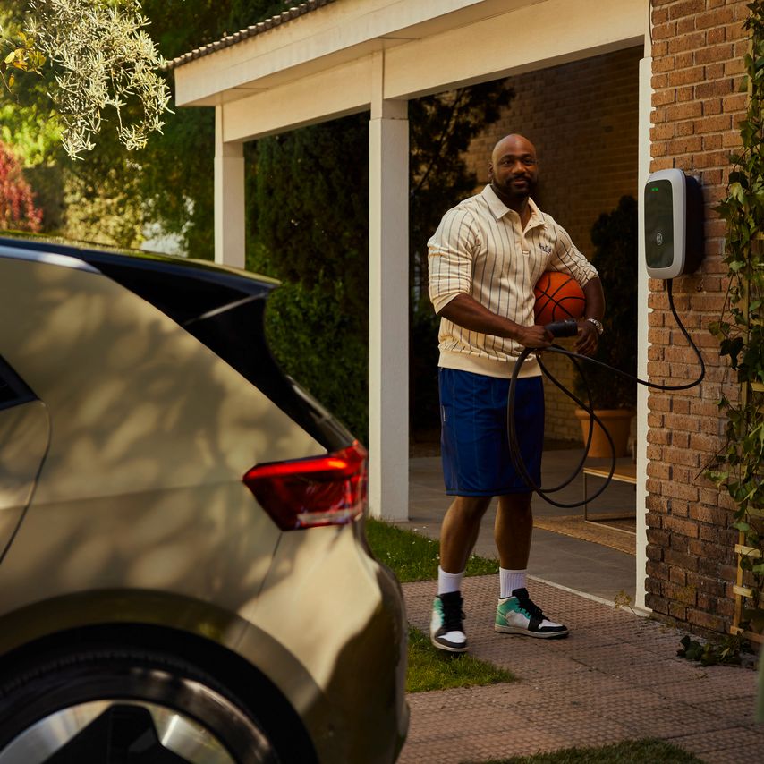 VW Connect / We Connect za modele ID. Moški se pogovarja s sosedom in drži polnilni kabel stenske polnilne postaje. V ospredju je Volkswagen ID.3