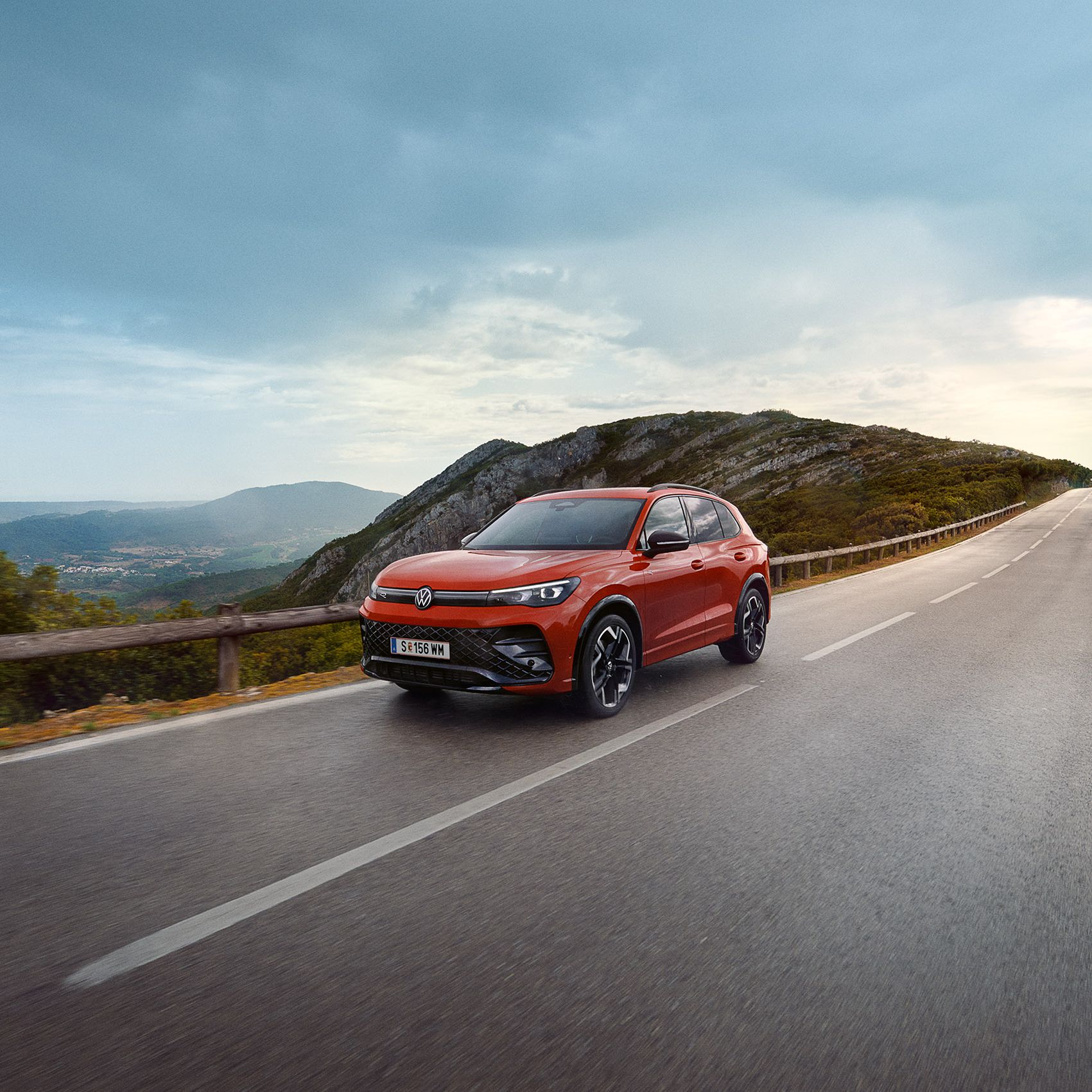 Rdeč VW Tiguan vozi po cesti.