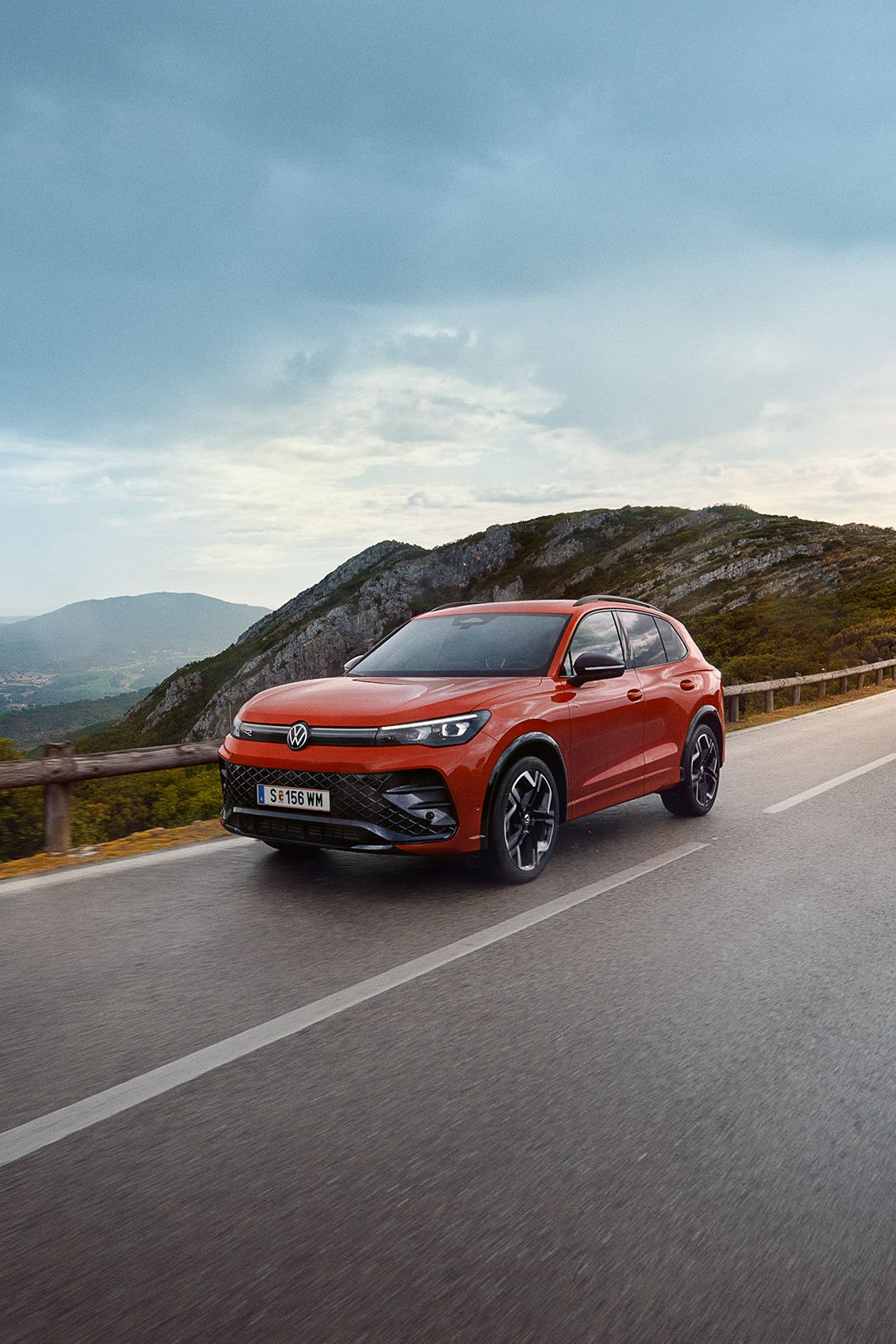 Rdeč VW Tiguan vozi po cesti.