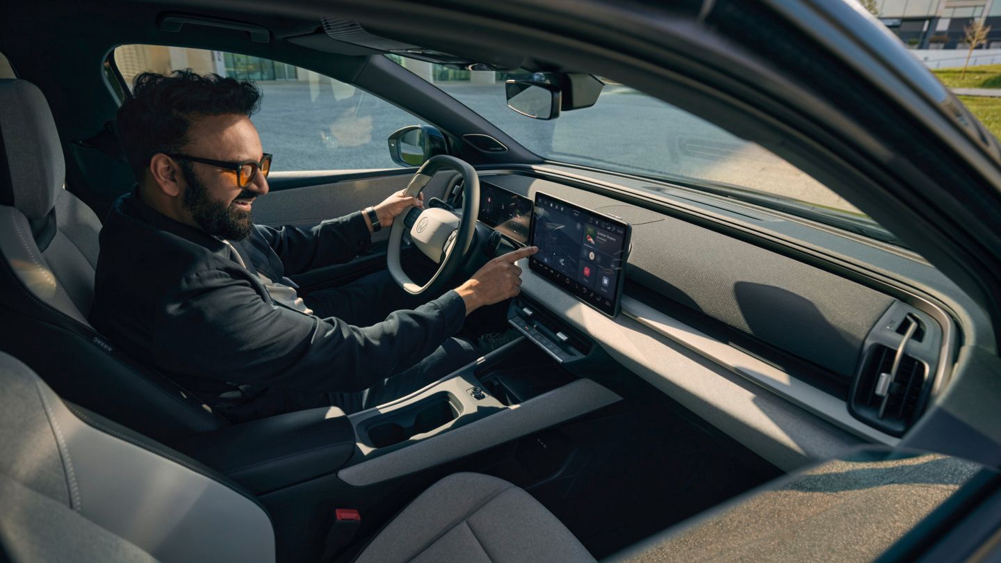 Moški sedi v VW ID. Cross in upravlja infotainment sistem.