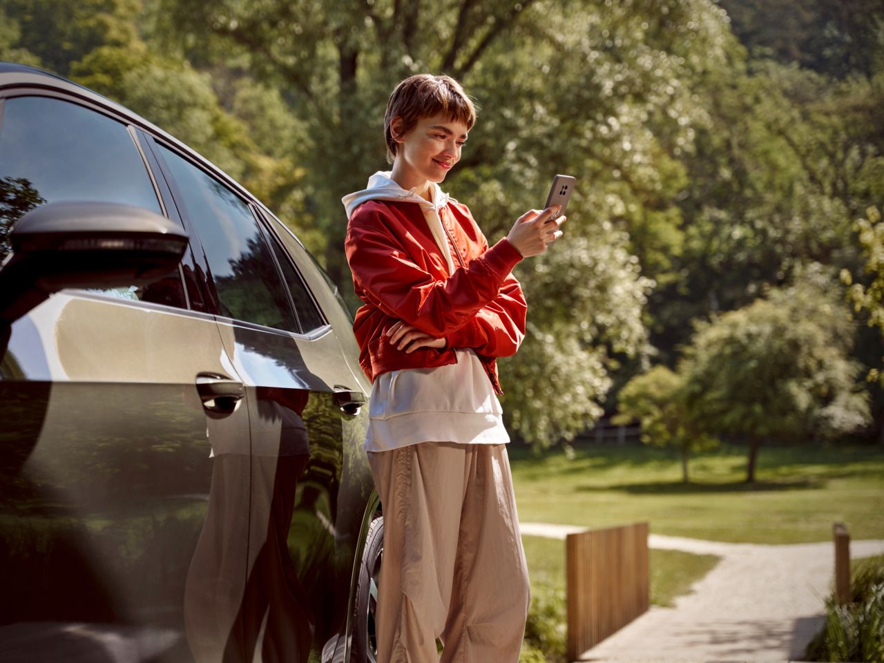 Ženska s pametnim telefonom stoji desno poleg modela Volkswagen ID.3