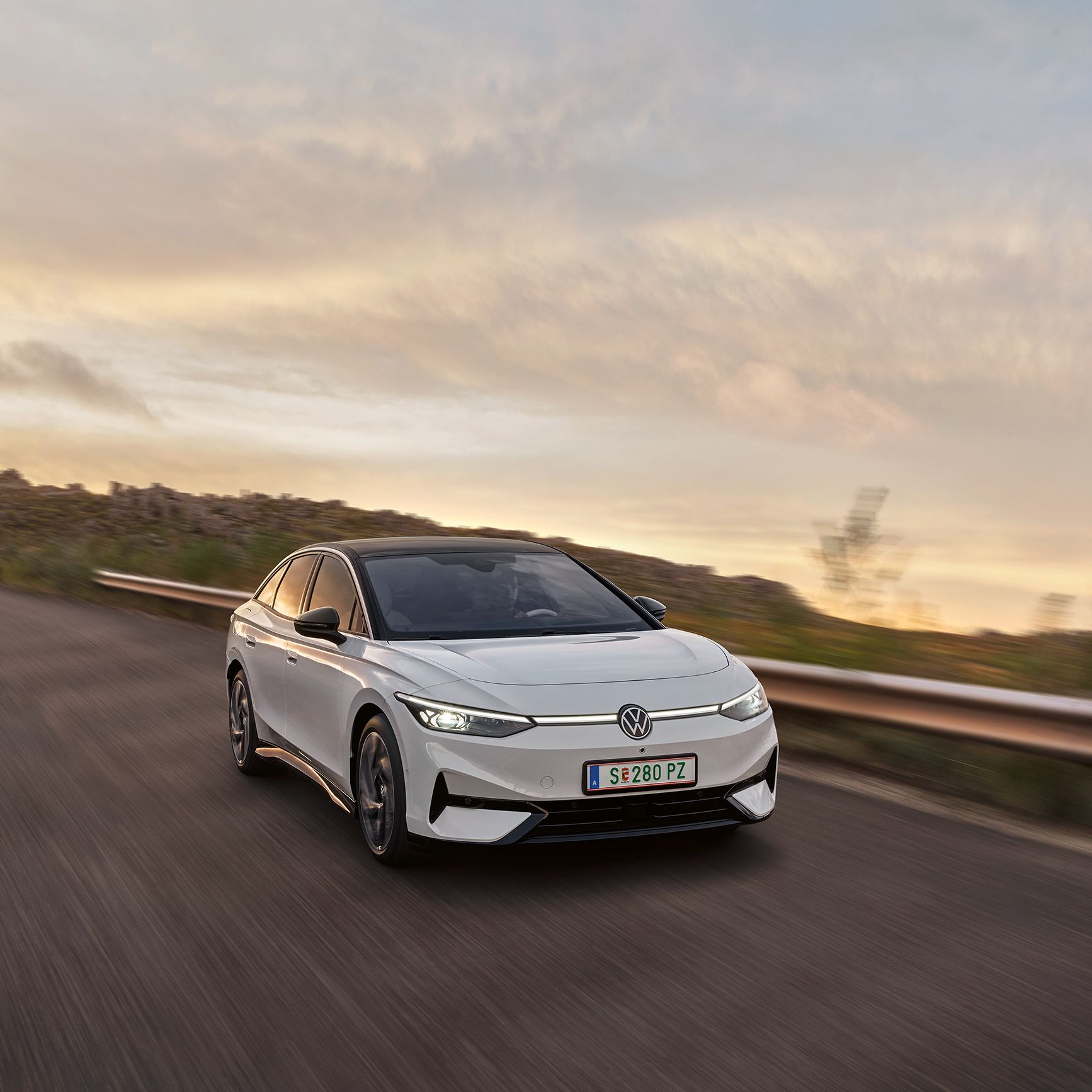 VW ID.7 vozi po regionalni cesti. Pogled na aerodinamično oblikovani sprednji del z žarometi IQ.LIGHT.