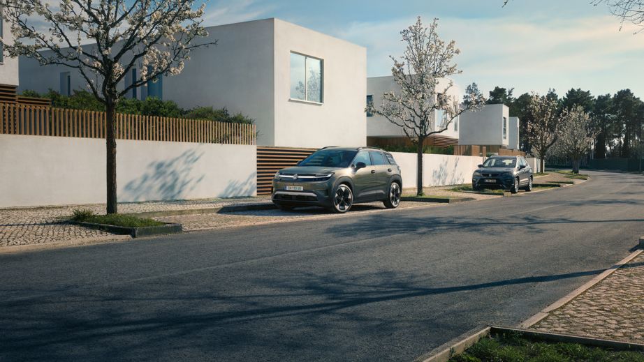 Zeleni VW ID. Cross parkira na parkirnem mestu v naselju s cvetočimi drevesi.