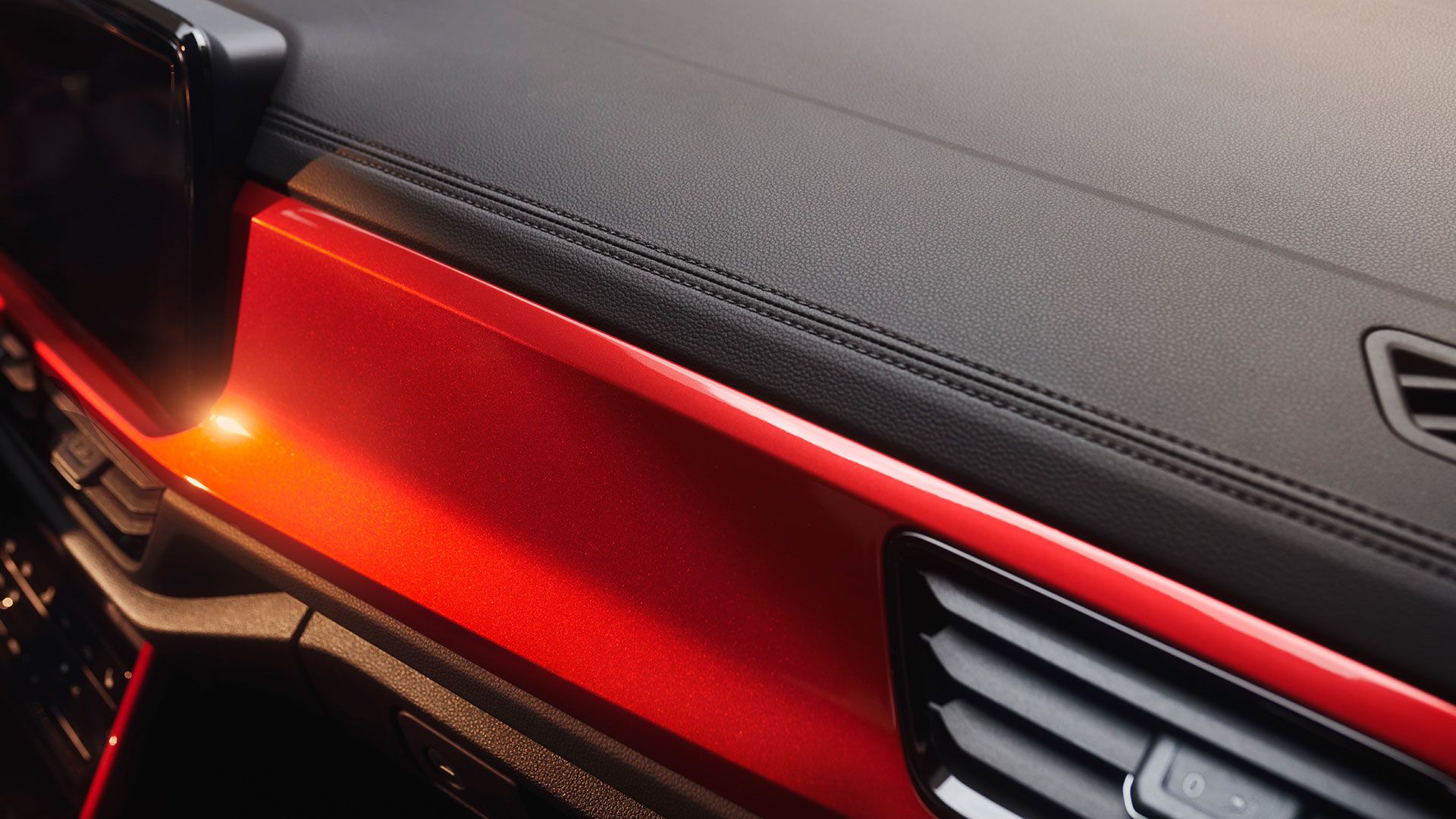 Detajlni posnetek okrasnih šivov na armaturni plošči VW T-Roc Cabrioleta z rdečimi dekorativnimi elementi.