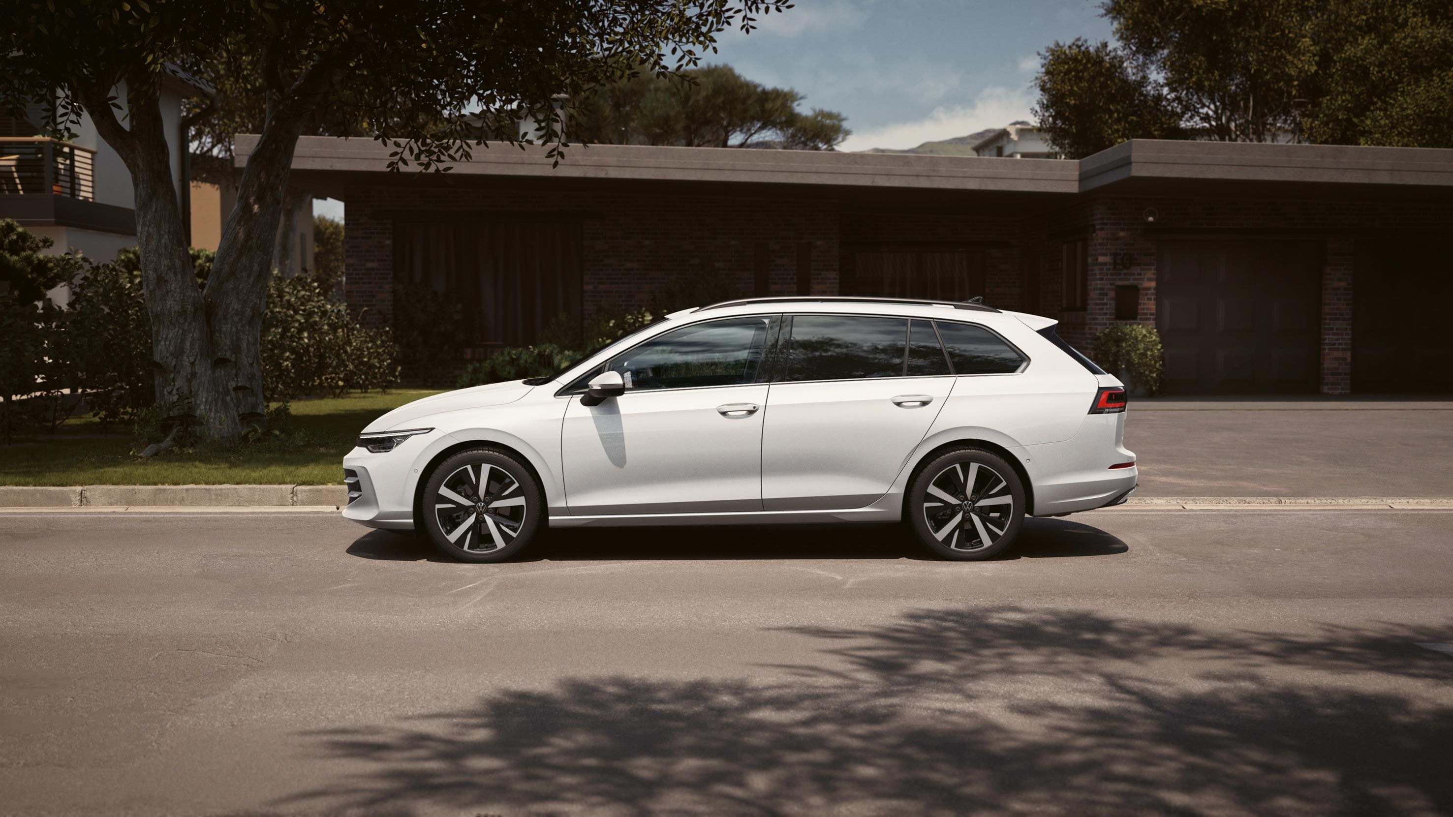 Bel VW Golf Variant je parkiran na dovozu pred garažo. 
