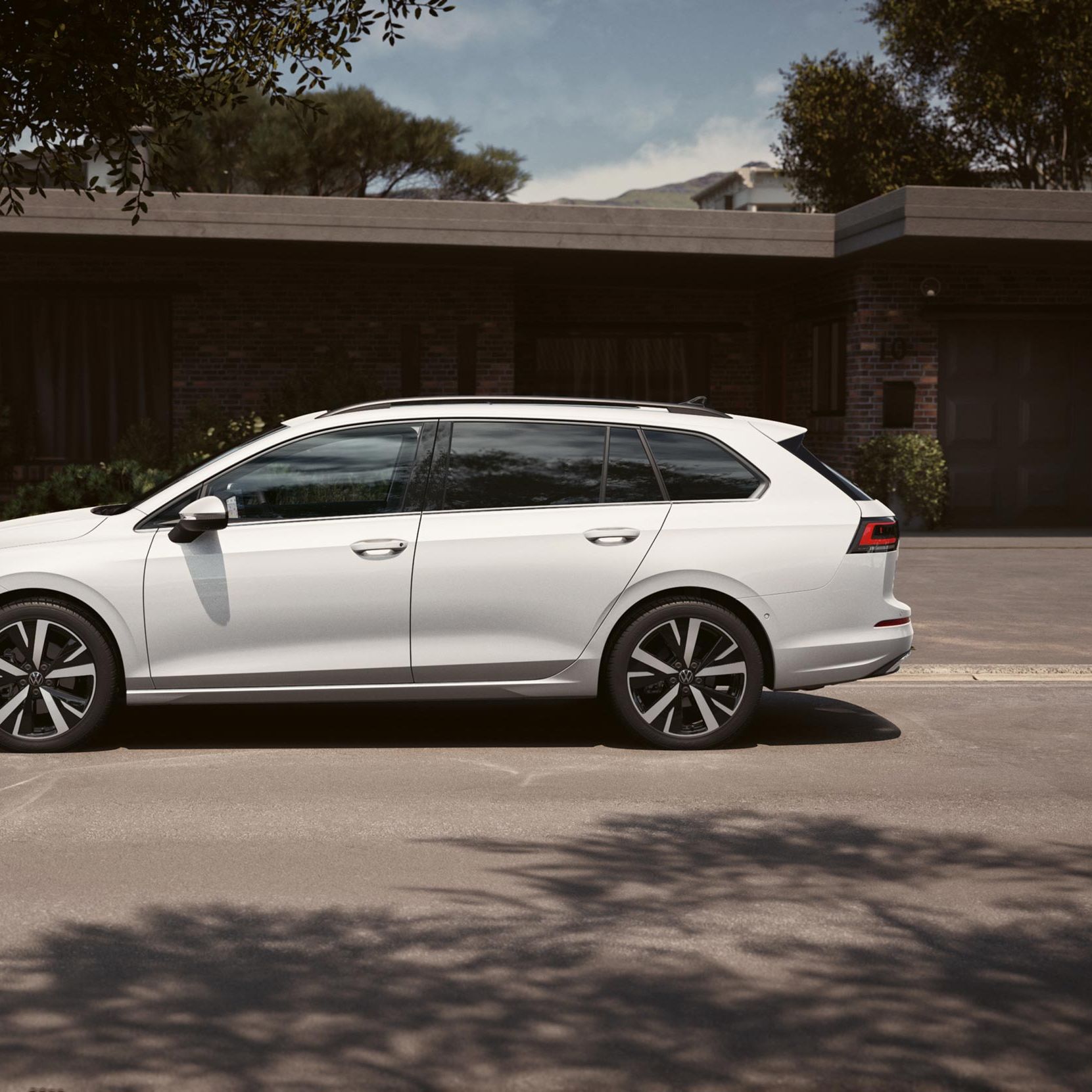 Bel VW Golf Variant je parkiran na dovozu pred garažo. 
